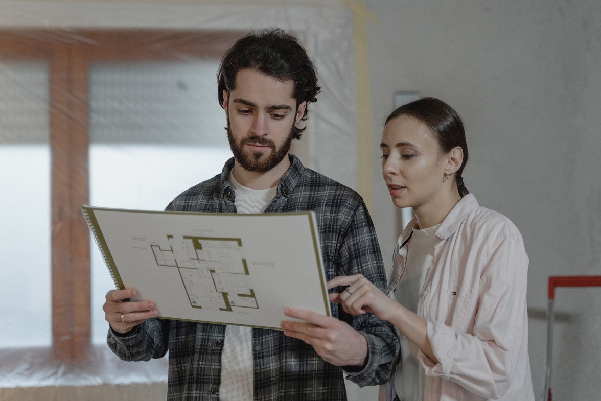 man and woman looking a blueprints
